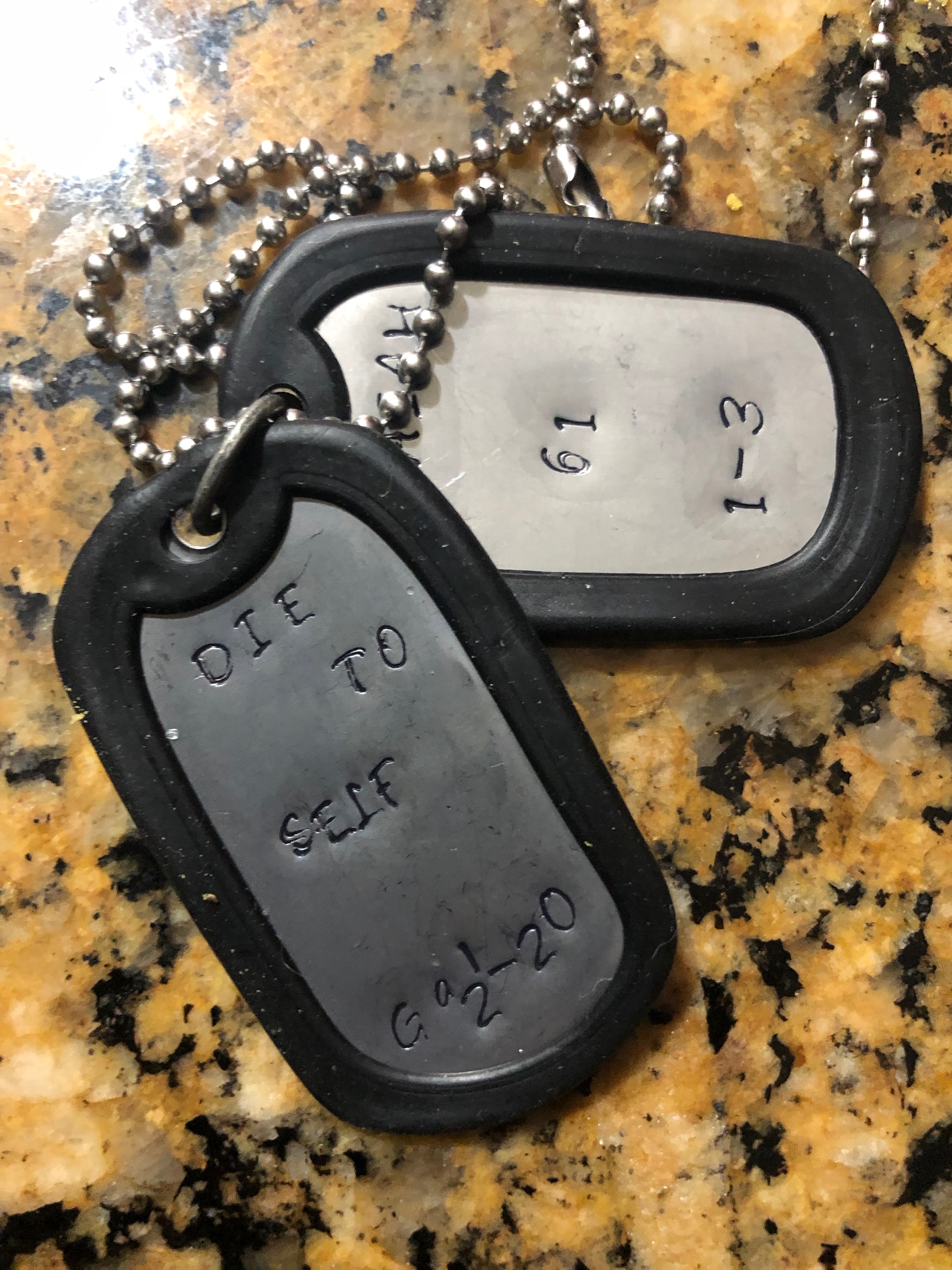 Two dog tags are sitting on a counter.