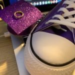A purple sneaker and a purse on top of a table.