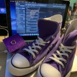 A pair of purple sneakers sitting on top of a laptop.