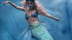 A woman in a blue and green mermaid costume.