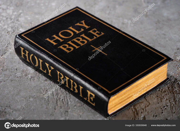 A black and gold bible sitting on top of the floor.