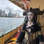 A woman dressed as a demon on the deck of a boat.
