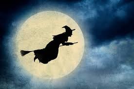 A witch flying in front of the moon.