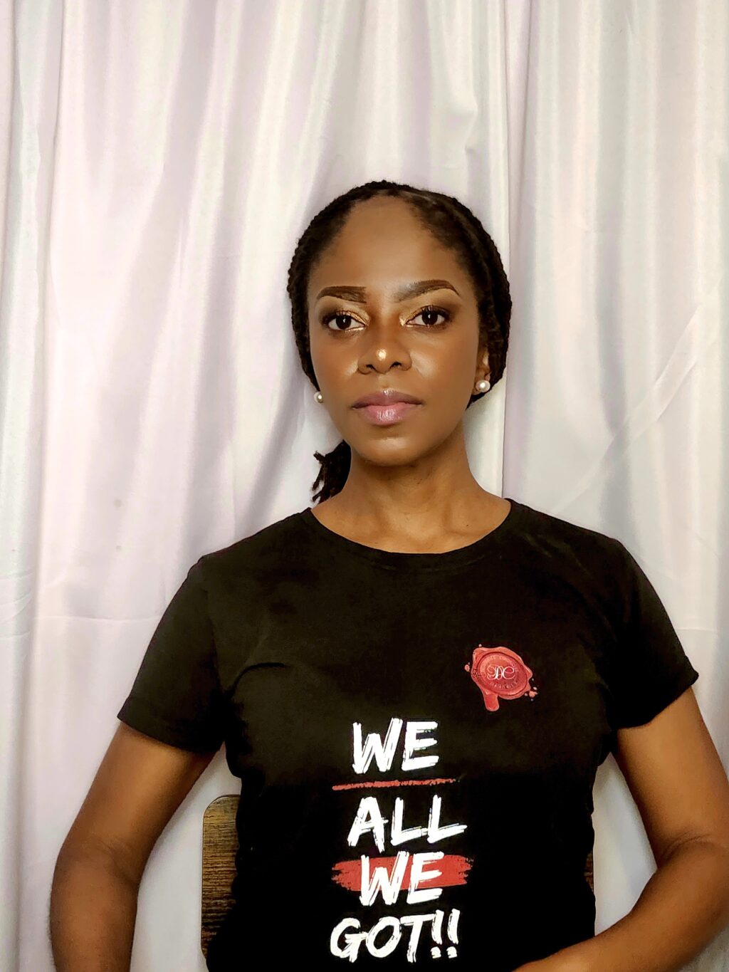 A woman wearing a black shirt with the words " we all " on it.