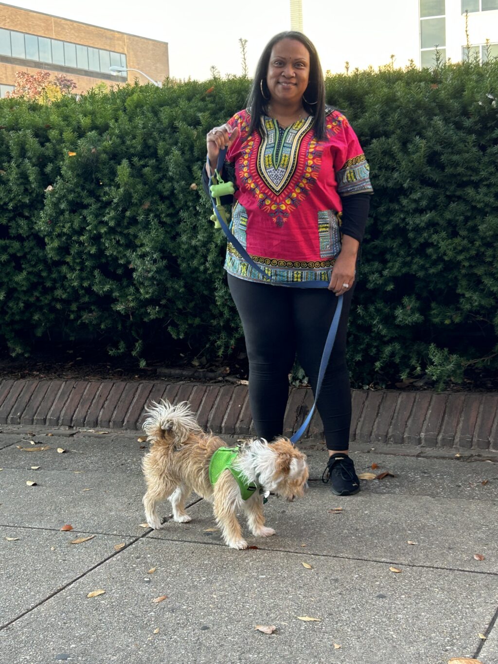 A woman is walking her dog on the sidewalk