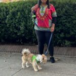 A woman is walking her dog on the sidewalk